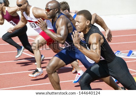 Side view of multiethnic male athletics sprinting on running track