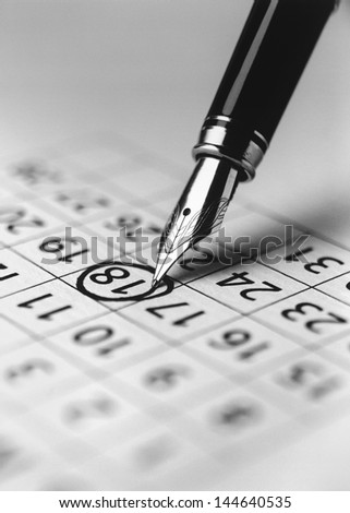 Tip of fountain pen marking date in calendar (b&w) (close-up)