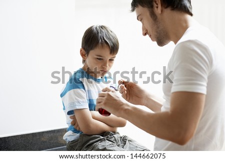 Father giving son cough syrup at home