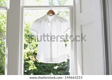 Blouse on hanger at domestic window