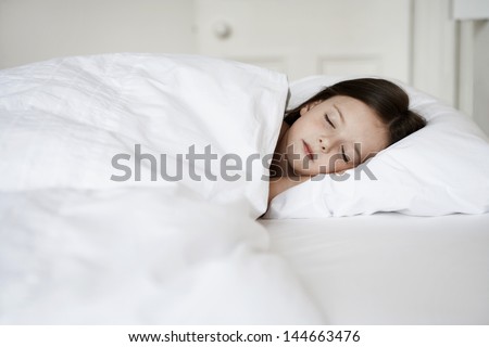 Little girl sleeping in bed cover with white blanket