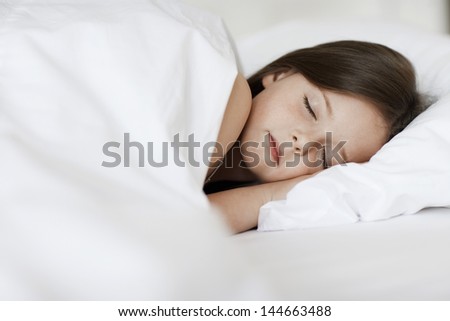 Closeup of young girl sleeping in bed cover with white blanket