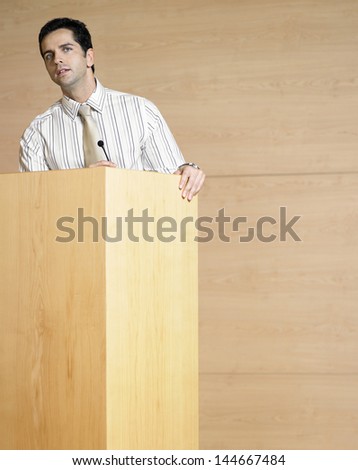 Young businessman talking at podium in conference room
