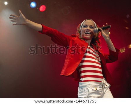 Low Angle View Of A Beautiful Young Woman Singing Into Microphone On Stage
