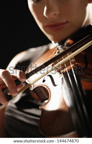 Closeup of a woman playing the violin against black background