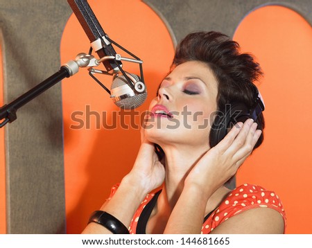 Closeup of a gorgeous female singer recording a track in a studio