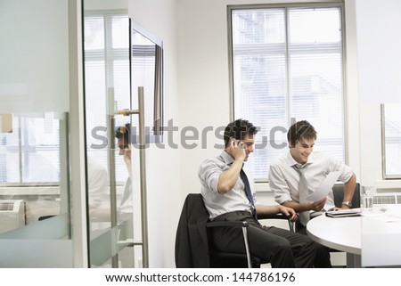 View through doorway to casual meeting between two relaxed young businessmen