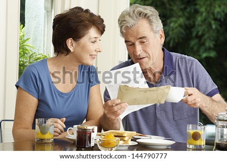 Middle aged couple looking at bills over breakfast in the house
