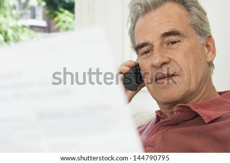 Closeup of a middle aged man using cell phone and looking at bill