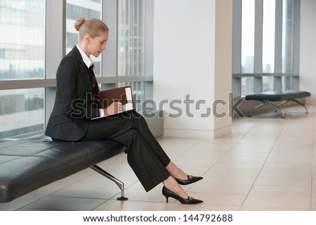 Side view of a businesswoman writing in planner at the office lobby