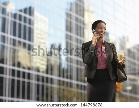 Smiling African American Businesswoman Using Mobile Phone On Street Against Building