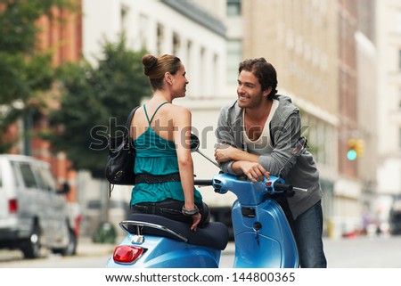 Woman On Moped Talking To Man In Street