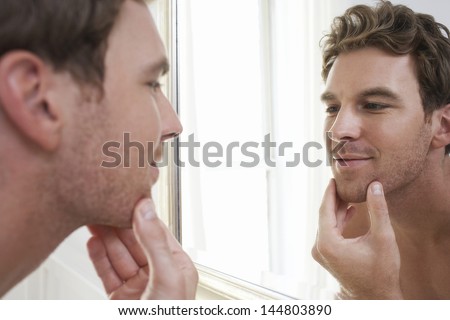Closeup of a young man examining his stubble in mirror