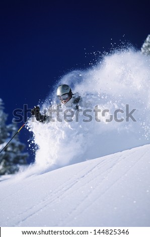 Skier in deep powder snow against deep blue sky