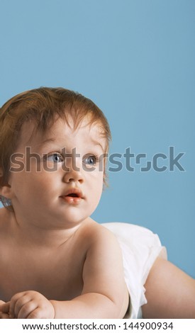Cute baby boy lying on front isolated on blue background