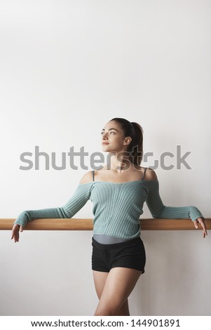 Young female ballet dancer practicing at bar