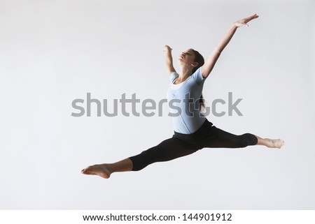 Full length of female ballet dancer leaping in mid air isolated on white background