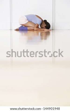 Side view of young ballerina in prayer position at rehearsal room