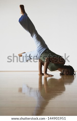 Young male ballet dancer doing handstand in rehearsal room