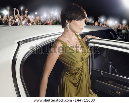 Beautiful Young Woman In Evening Wear Getting Out Of Limousine In Front Of Fans And Paparazzi
