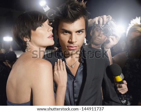 Portrait of young celebrity couple surrounded by paparazzi