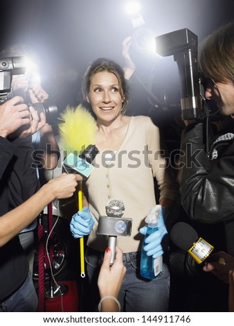 Middle aged woman with cleaning equipment being photographed by paparazzi