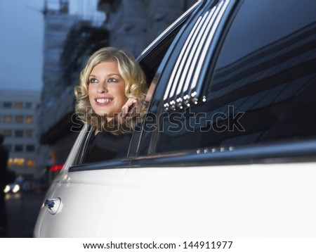 Smiling young female celebrity in limousine looking out of window