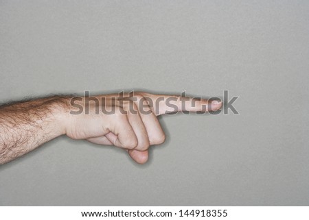 Closeup side view of hand pointing with index finger against gray background