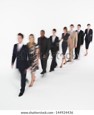 Full length of multiethnic businesspeople walking in blurred motion against white background
