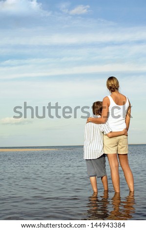 Rear view of mother and son enjoying the sea view