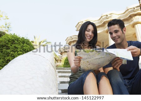 Young couple reading map while sitting on steps