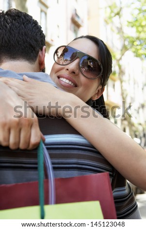 Romantic young woman with shopping bags embracing man during vacations
