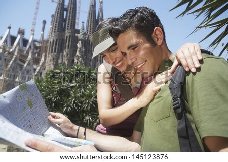 Happy Young Couple Reading Map Together At Barcelona
