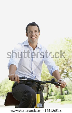 Happy businessman commuting on bicycle along road