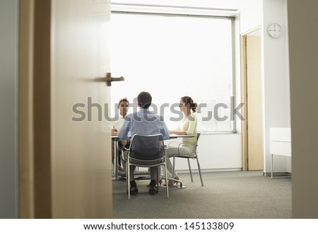 View Of Businessmen And Businesswoman Having A Meeting In Boardroom Though Doorway