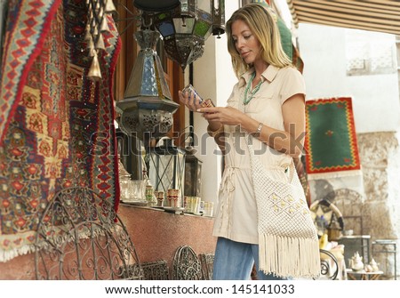 Happy middle aged woman shopping at souvenir stall