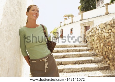 Happy middle aged woman on steps leaning on wall in Granada; Spain