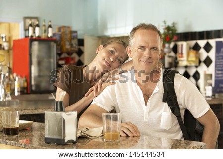 Portrait of happy middle aged woman relaxing on man\'s shoulder in bar