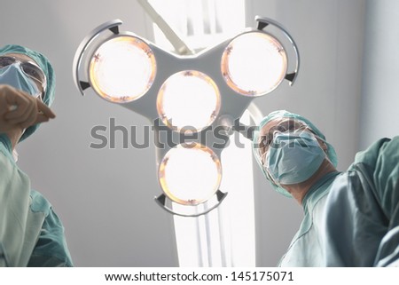 Low angle view of two surgeons under surgery lights in operating theatre