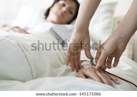 Closeup Of Hands Attaching Intravenous Tube To Patient\'S Hand In Hospital Bed