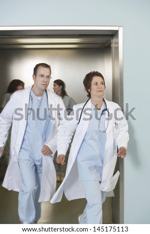 Male and female doctors running out of elevator