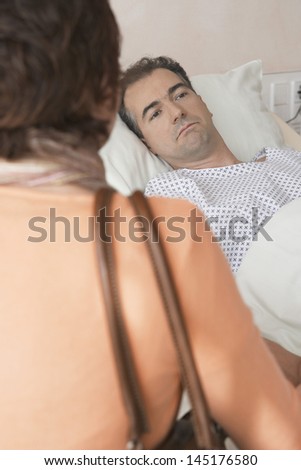 Closeup rear view of a woman visiting man in hospital