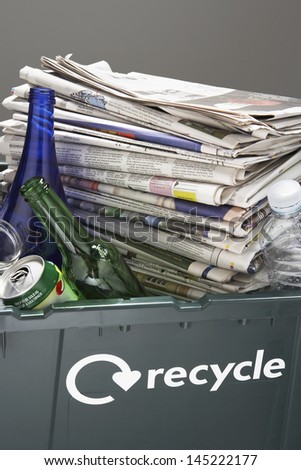 Recycling bin filled with waste paper and bottles close-up