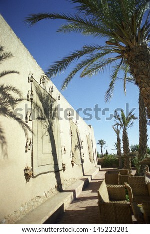 Building exterior with palm trees and wicker furniture
