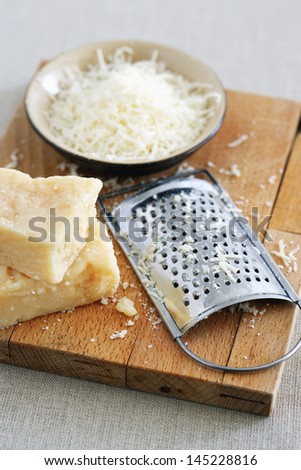 Parmesan cheese and grater on cutting board at table