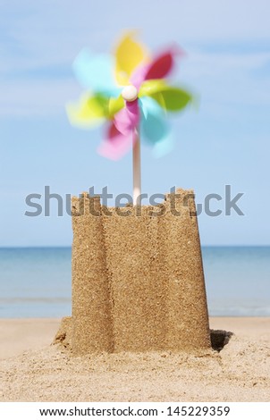 Sand castle with moving pinwheel on beach close-up