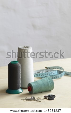 Spools of thead pins and measuring tape on table