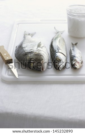 Three fishes on chopping board close-up