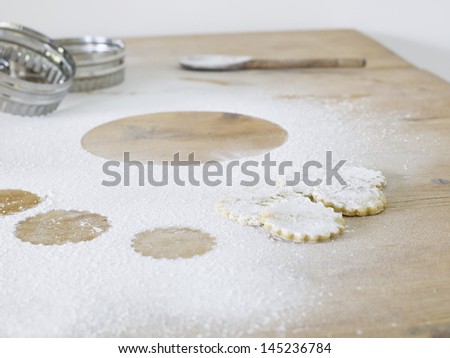 Pastry cutters cookies and flour scattered on table close up