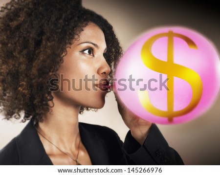 Closeup of a businesswoman blowing up balloon with dollar sign against brown background